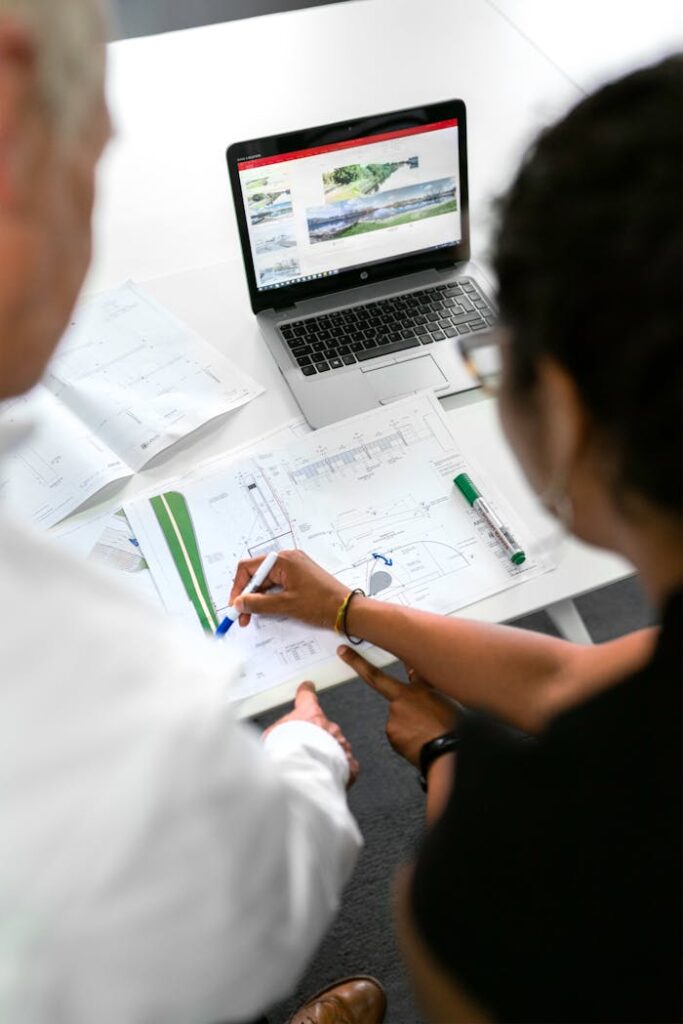 pexels-photo-3862365 Engineers collaborate on designs with blueprints and laptops in a modern office setting.